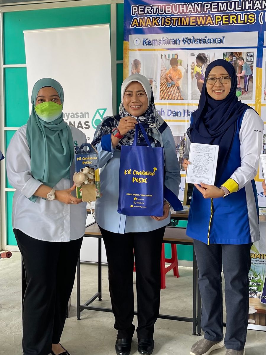 Julika Ishak, Head of Planning and Services of Yayasan PETRONAS (left), with YB Rozieana Ahmad, Perlis State Executive Councillor of Education (center), and Nazmin Abdullah, Director of Perlis Special Teens Centre (PeSTeC) (right) showcasing the mushroom kit, which is one of the products produced by PeSTeC.